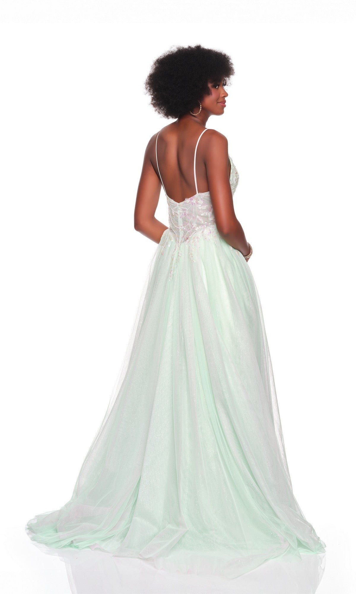 Woman wearing the Dave and Johnny 12687 long prom dress in light green, featuring an embroidered bodice, backless design, thin straps, and delicate lace details, standing against a white background.